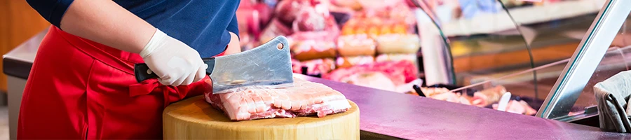 A woman chopping meat on a chopping board