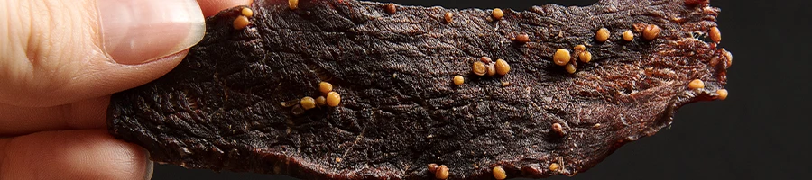 A woman holding a piece of beef jerky