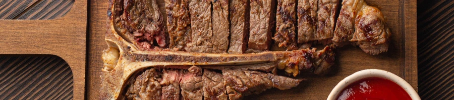 A top view image of T-bone steak on a cutting board