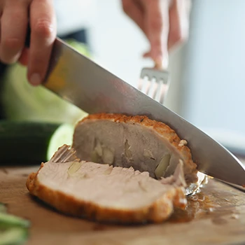 A person slicing a meat on a cutting board