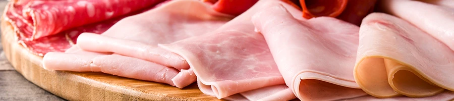 A close up image of deli meat on a cutting board