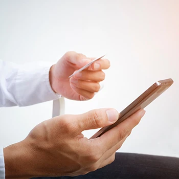 A person holding a phone and a credit card