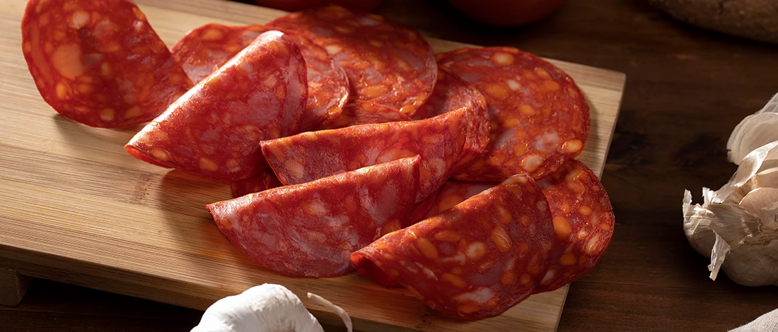 An image of sliced deli meat on a wooden cutting board