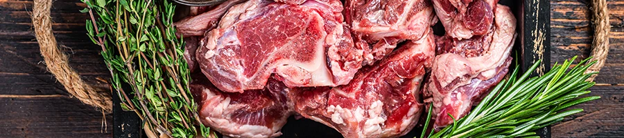 A top view image of raw goat meat on a wooden container