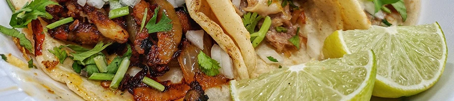 An image of taco de buche and limes on a plate