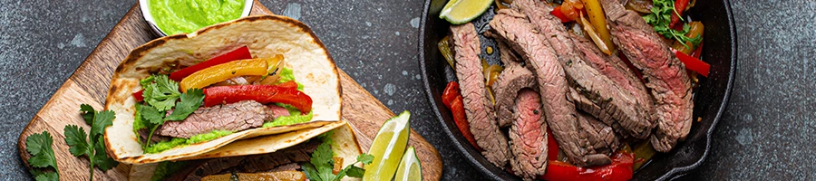 Fajita dishes on a wooden board and a pan