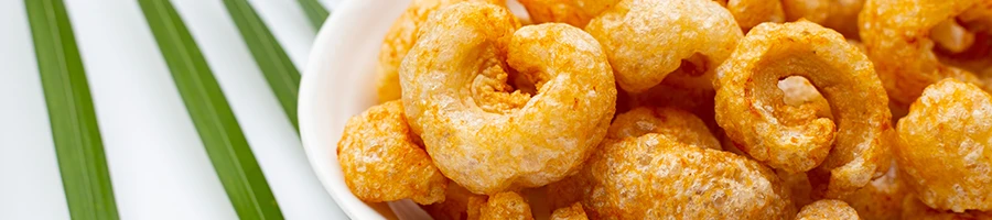 An image of pork rinds on a plate and plant leaves under