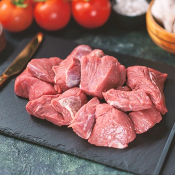 An image of raw beef chunks on a black slate