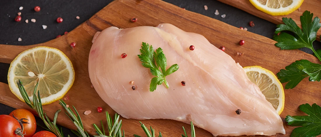 A top view image of chicken breast meat on a wooden board