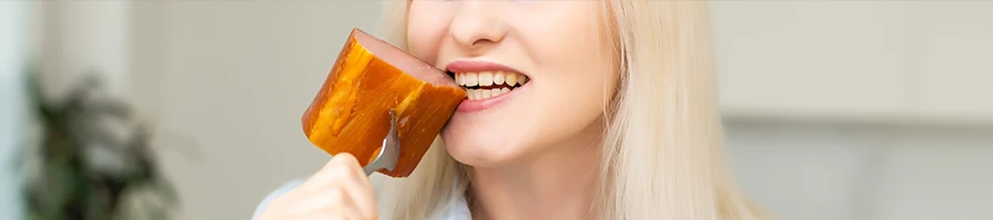 A close up image of a woman biting meat from a fork