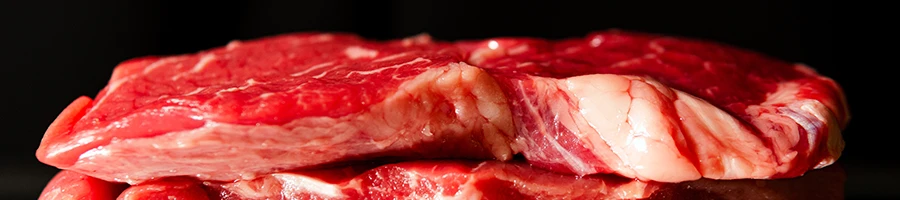 A close up image of uncovered raw steak with dark background