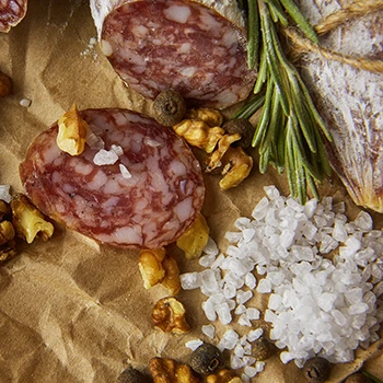 A close up image of cured meat, salt, and other ingredients
