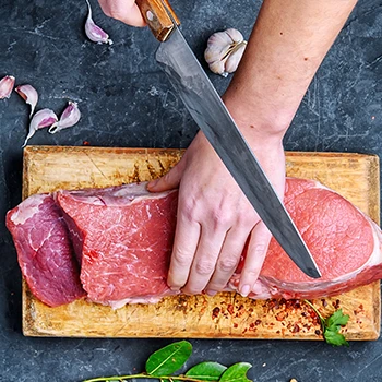 A top view image of a person slicing fresh beef meat