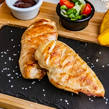 An image of grilled chicken meat on a top of a black slate
