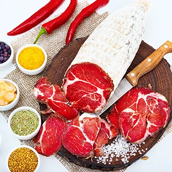A top view image of capicola meat and different herbs and spices