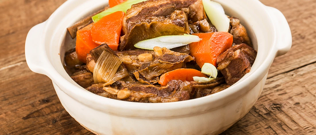 An image of braised meat dish in a white bowl
