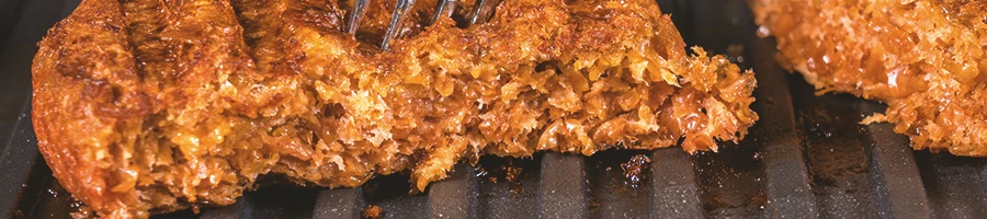 An image of plant-based meat being cooked on a grill