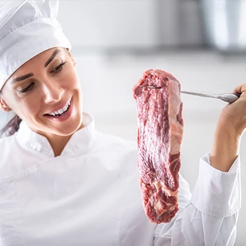 A chef inspecting beef meat on a knife