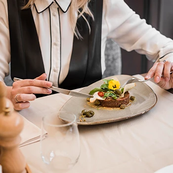 An image of a woman eating steak at a fine restaurant