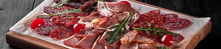 Different processed meats on top of a wooden board