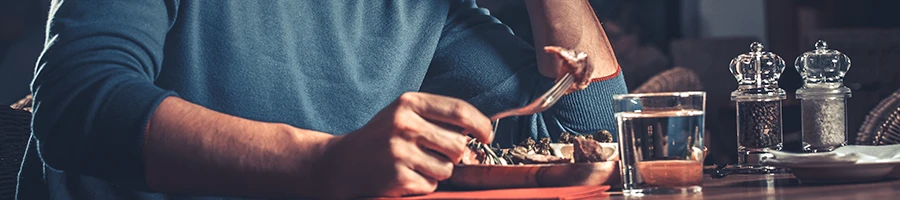 An image of a guy eating meat on a table