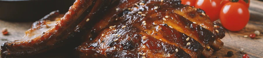 A close up image of pork rib roast with tomatoes at the back