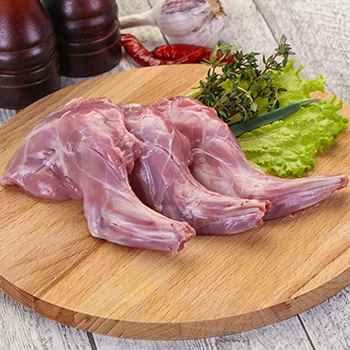 A close up image of raw rabbit leg meat on a wooden board