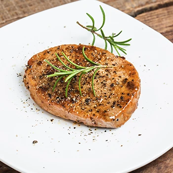 A close up image of cooked round steak on a white plate