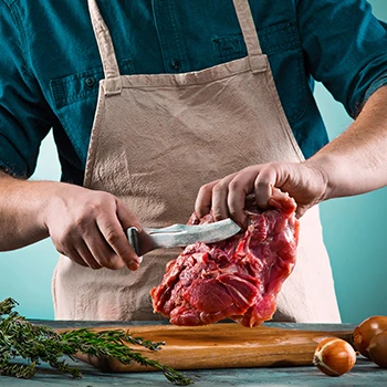 A butcher slicing raw beef meat