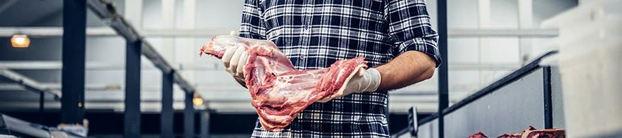 A butcher holding a raw kosher meat