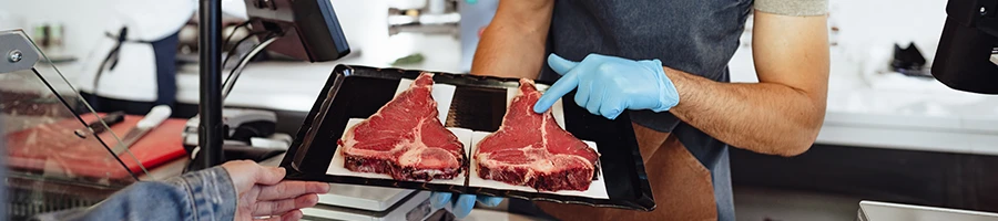 A butcher recommending gluten-free meat to a customer