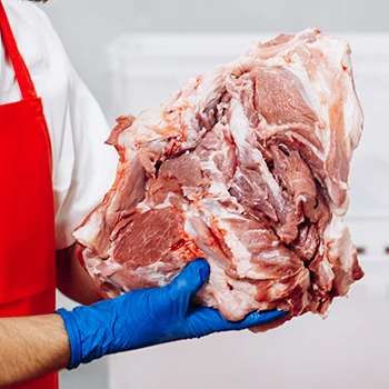 A butcher holding a huge piece of beef meat