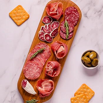 A top view image of cured meats on a wooden board