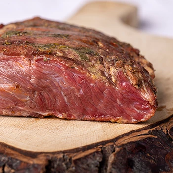 An image of pastrami meat placed on top of a wooden board