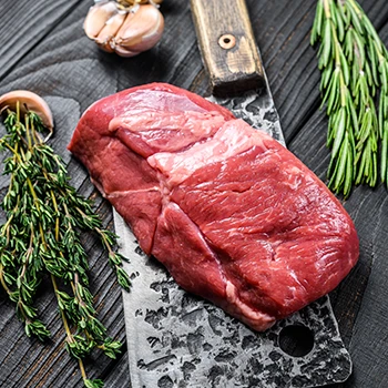 An image of raw veal meat on top of a butcher knife