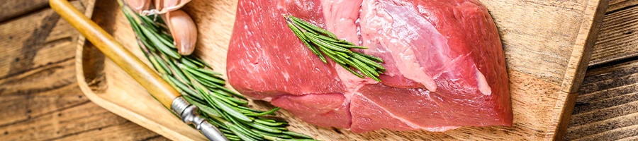 An image of raw veal meat on a wooden board