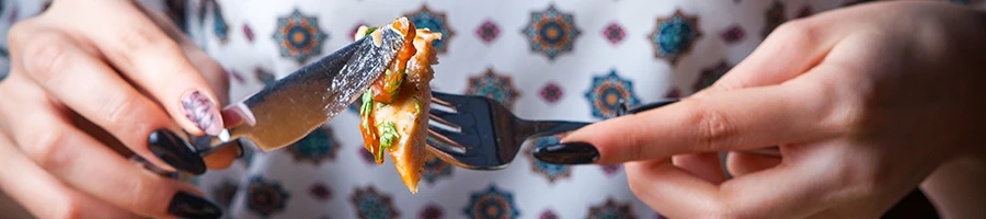 A woman eating meat using a knife and fork