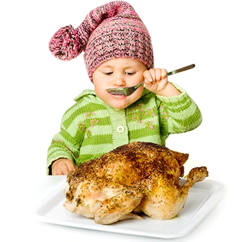 A baby standing in front of a cooked chicken while eating using a fork