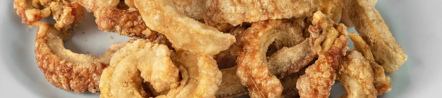A close up image of crispy pork rinds on a white plate