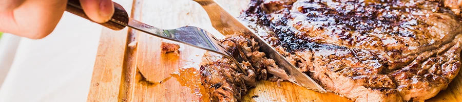 An image of a person slicing a steak on a wooden board