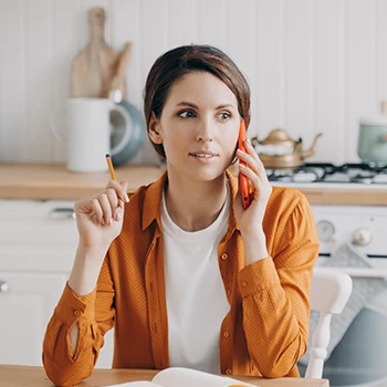 An image of a woman making a phone call at a kitchen