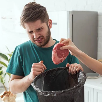 An image of a person who is about to throw meat at a trash bin