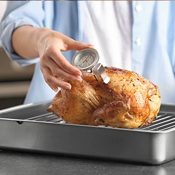 A chef checking the temperature of a cooked chicken using a meat thermometer