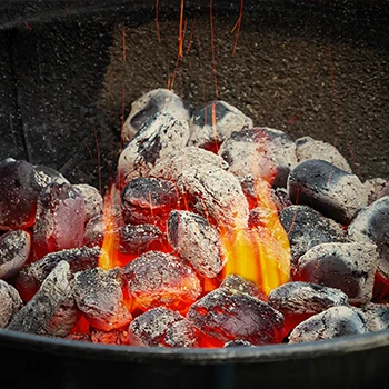 A close up image of charcoal in flames inside a drum smoker