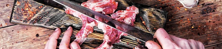 An image of a person slicing raw lamb red meat