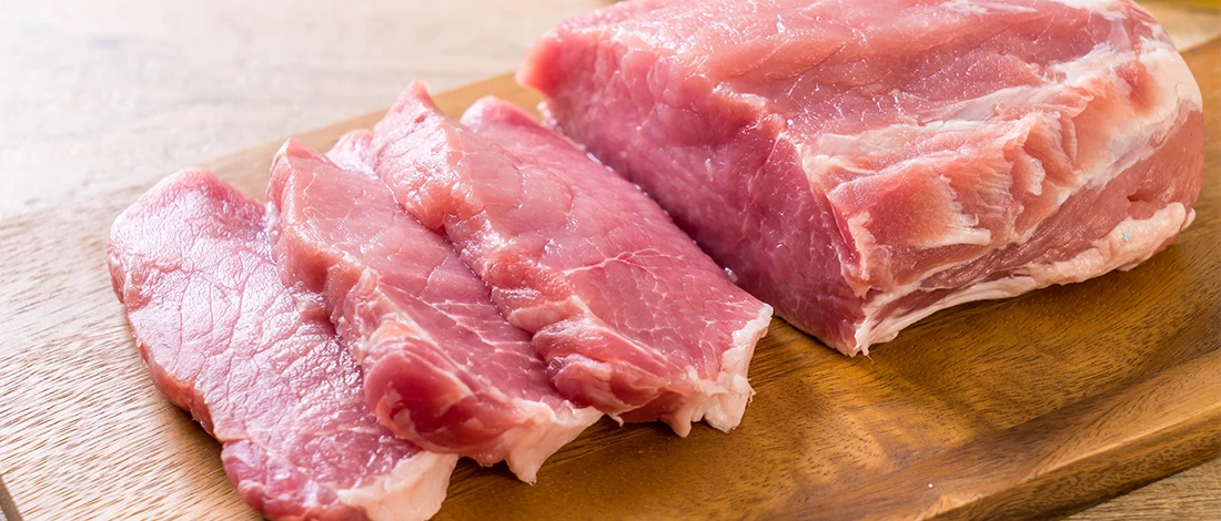 An image of pork meat on top of a wooden board