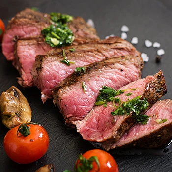 A close up image of sliced steak with salt and other garnishes