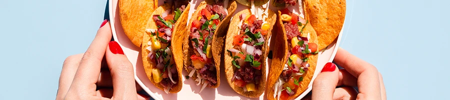 An image of a woman holding a plate full of tacos