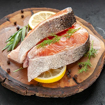 A close up image of raw fish meat with slices of lemon