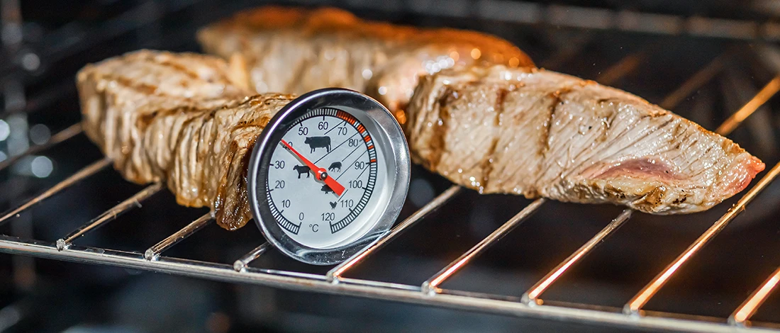 An image of a meat and meat thermometer inside an oven
